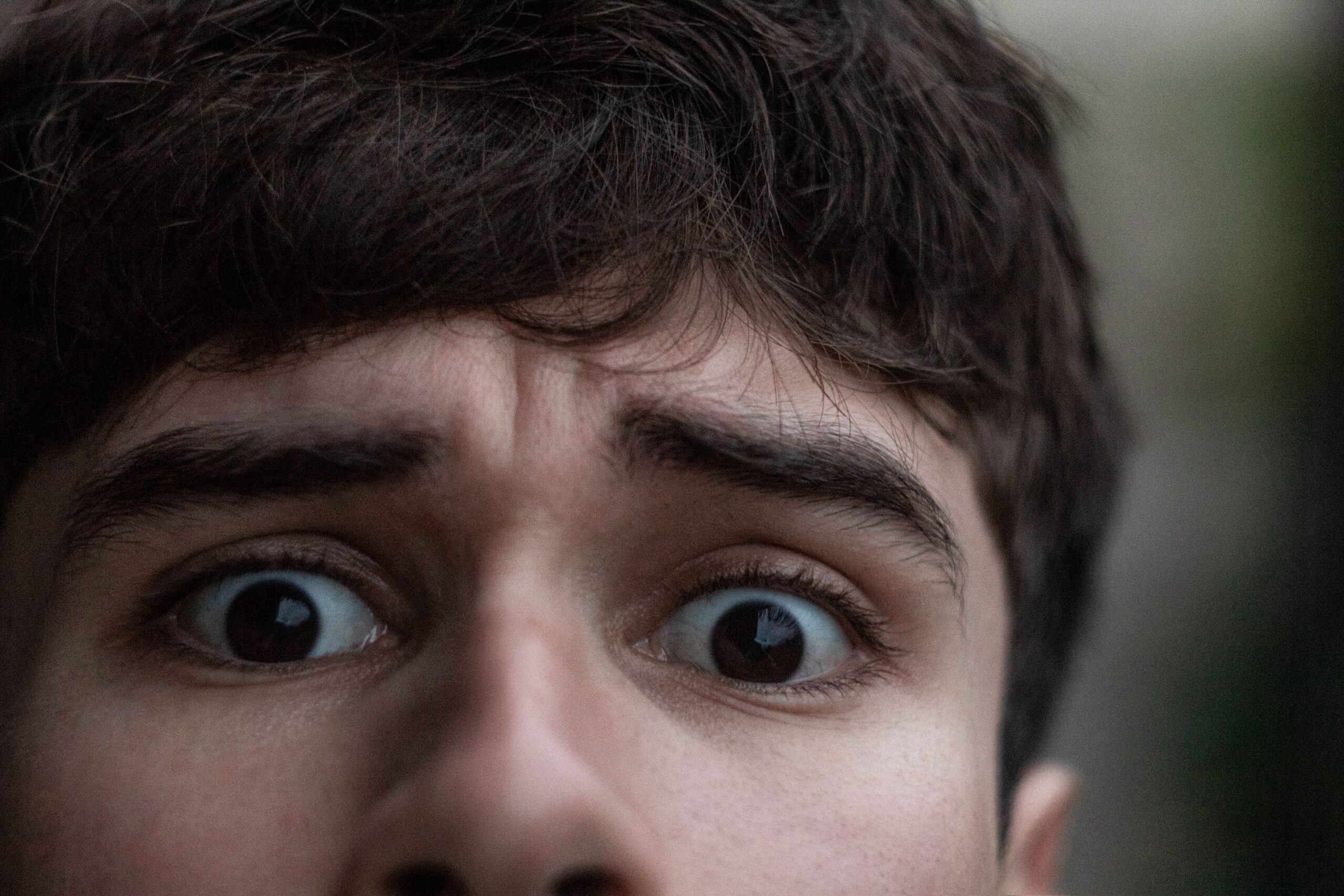 Primer plano de los ojos muy abiertos de un joven, con expresión de sorpresa y las cejas ligeramente arqueadas.