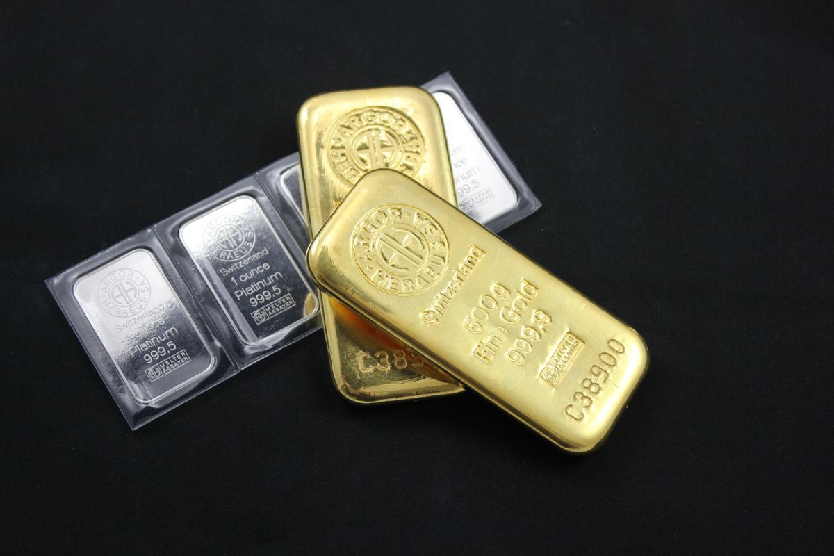 Lingotes de oro y plata apilados sobre un fondo negro.