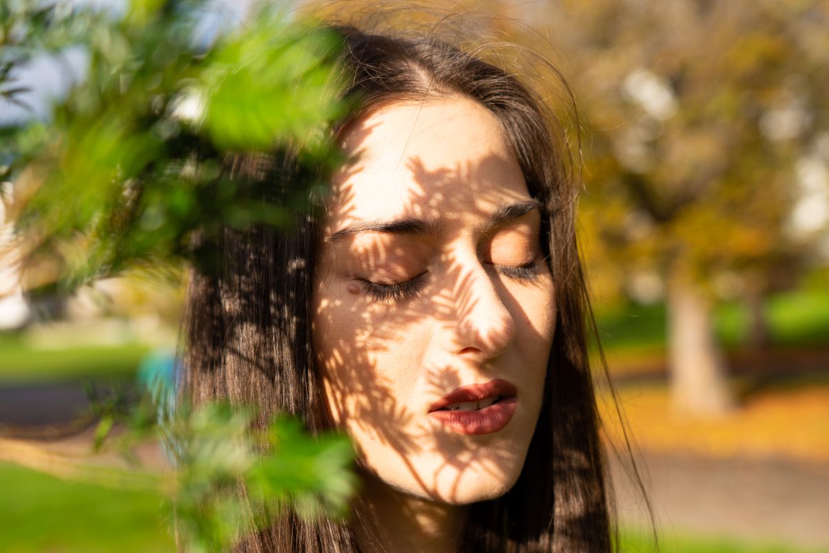 Una persona entrecierra los ojos y estornuda al salir a la calle bajo un sol intenso, ejemplo del síndrome ACHOO