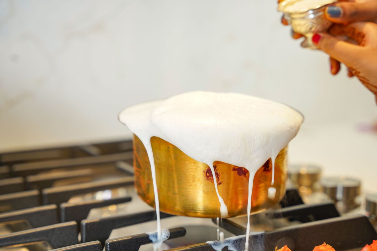 Una cuchara de madera colocada sobre una olla con agua hirviendo y espuma en la superficie.