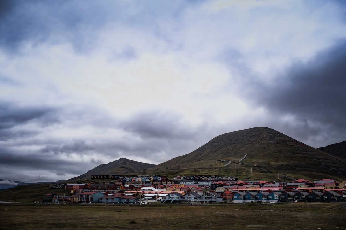 Cementerio nevado de Longyearbyen en Svalbard, con cruces de madera sobre el suelo helado del permafrost y montañas árticas al fondo bajo un cielo gris.