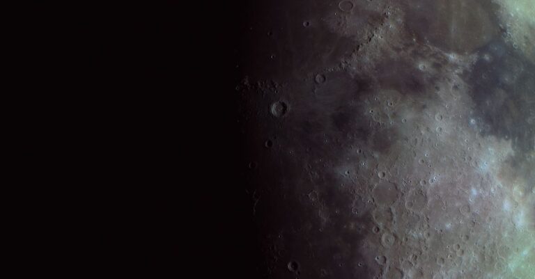 Superficie lunar llena de cráteres, fotografiada cerca de la línea entre la luz y la sombra.