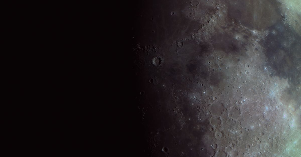 Superficie lunar llena de cráteres, fotografiada cerca de la línea entre la luz y la sombra.
