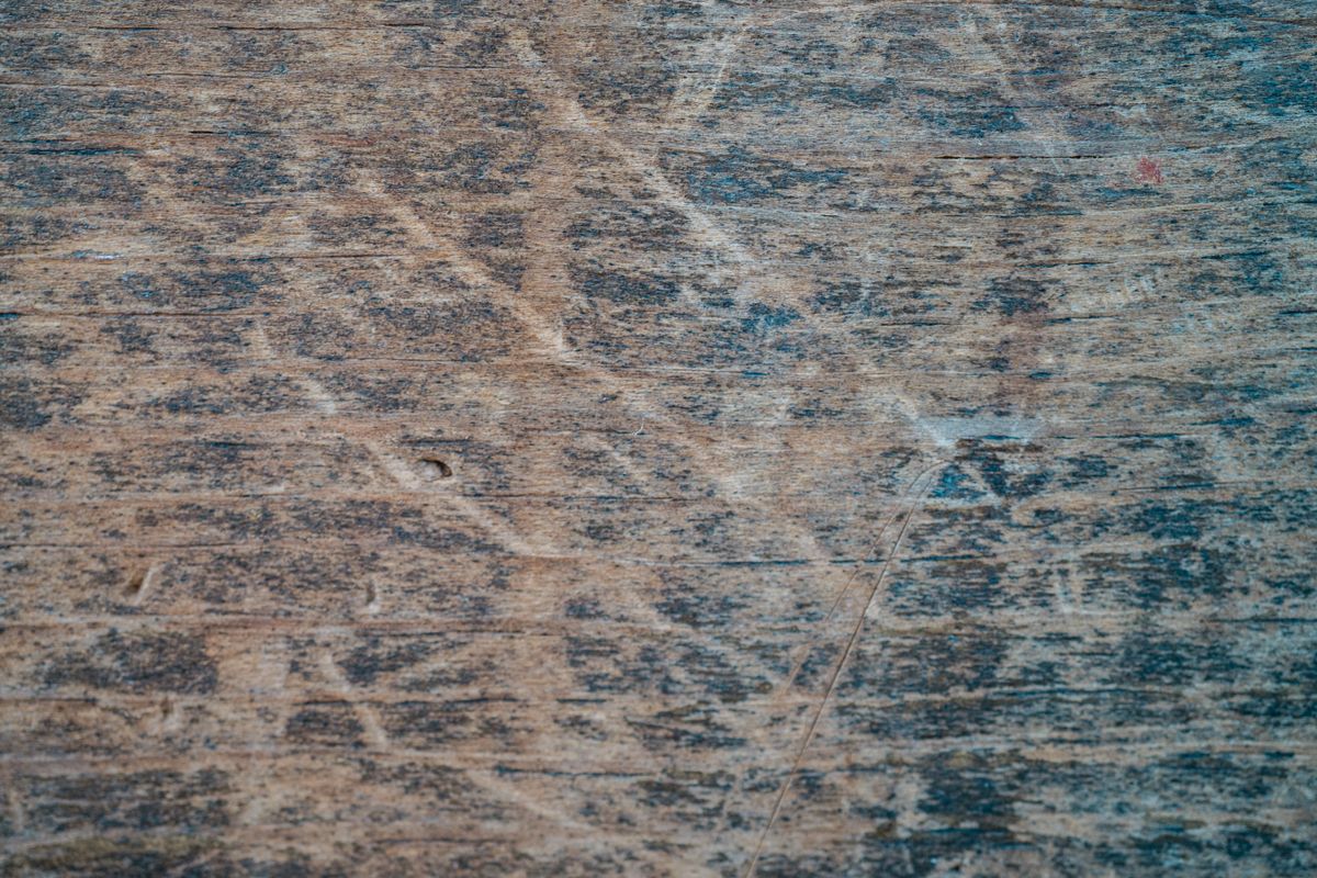 Media nuez partida junto a un mueble de madera con un arañazo, mostrando el truco casero para disimular arañazos de madera con aceite de nuez.