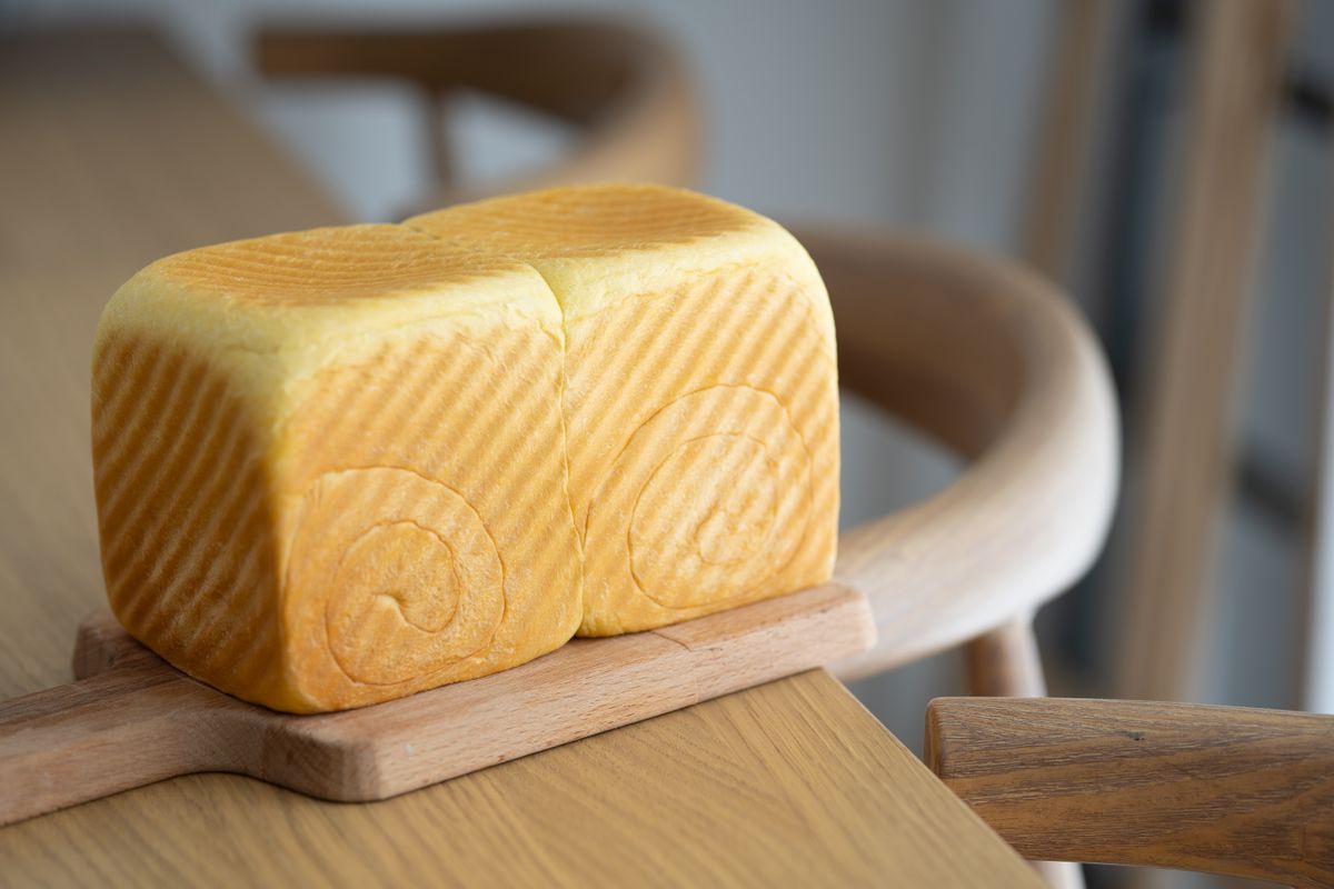 Pan de molde recién cortado por la mitad sobre una tabla de madera, mostrando la miga suave que ayuda a conservar el pan fresco antes de que se ponga duro.
